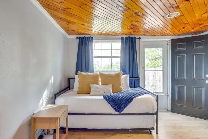 Twin bedroom featuring a beautiful wood ceiling, blue drapes, and plenty of natural light — a standout room that guests won't expect.