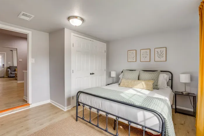 Guest bedroom with queen bed, iron frame, and closet storage — a clean and comfortable space with easy access to the rest of the home.