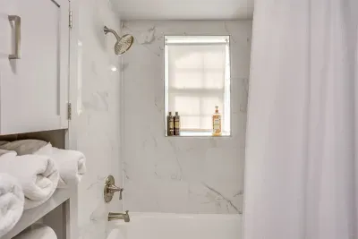 Full shower and tub combo with fresh towels and toiletries provided — clean, bright, and ready for your group.