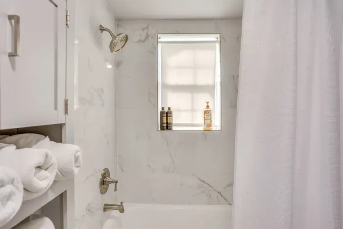 Full shower and tub combo with fresh towels and toiletries provided — clean, bright, and ready for your group.