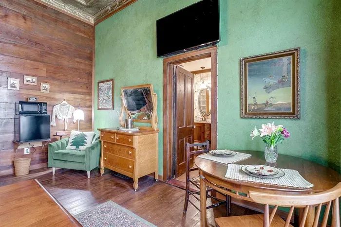 Convenient in-room amenities include a smart TV, mini fridge, microwave, and a charming dining table for added comfort