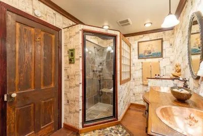 The spacious bathroom features a stunning walk-in shower and double copper vanity, offering ample space and high-end finishes for your ultimate relaxation and convenience.