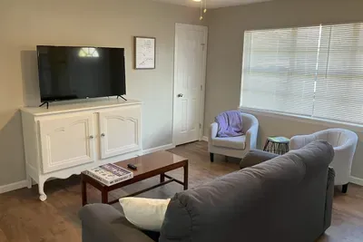 Bright and cozy living room with a smart TV, plush couch, and inviting decor, perfect for relaxing after exploring Stephenville