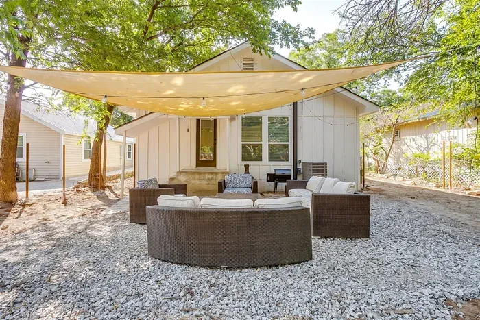 Relax in the spacious private backyard featuring shaded seating and stylish patio furniture — perfect for outdoor lounging year-round.