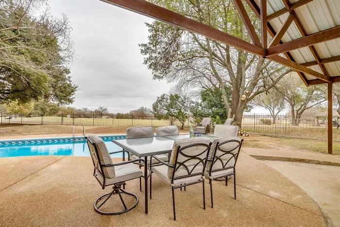 Relax in the shade on the covered patio with comfortable seating, offering a peaceful retreat with views of the pool and golf course