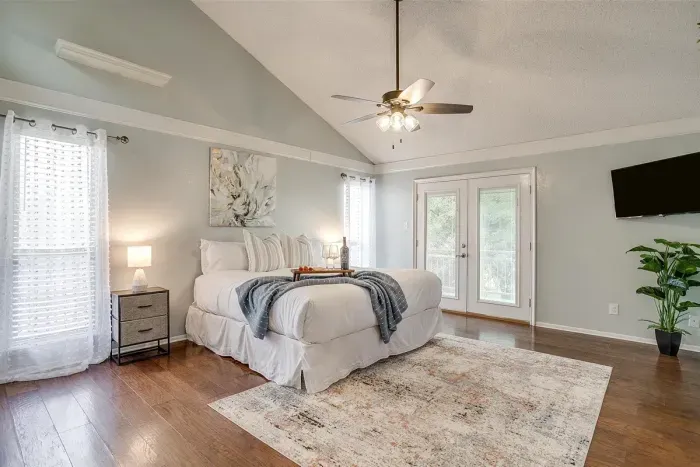 Spacious master bedroom featuring a king-size bed with plush linens, a smart TV, and private balcony access for a luxurious and restful experience