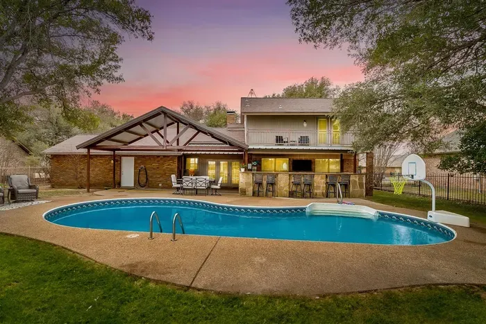 Relax in your private backyard oasis featuring a sparkling pool with a basketball hoop, surrounded by lush greenery and views of the golf course. Perfect for family fun or peaceful retreats