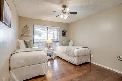 Charming third bedroom with two twin beds, stylish decor, and a smart TV, ideal for kids or extra guests