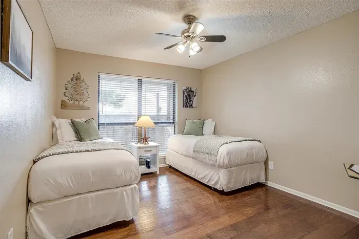 Charming third bedroom with two twin beds, stylish decor, and a smart TV, ideal for kids or extra guests