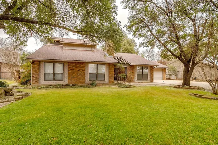 Welcoming front yard with mature trees, a large driveway, and charming curb appeal that invites you into this beautiful vacation home