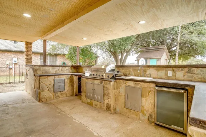 State-of-the-art outdoor kitchen complete with a gas BBQ grill, smart TV, and ample counter space, perfect for entertaining and al fresco dining