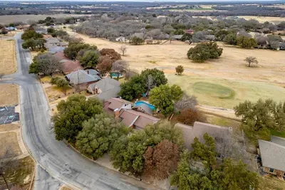 Drone view showcasing the home’s spacious layout, lush backyard, and prime location near the golf course