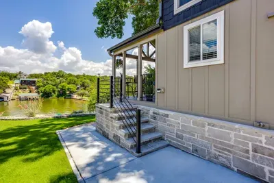 Covered porch steps down to the lawn and lake beyond