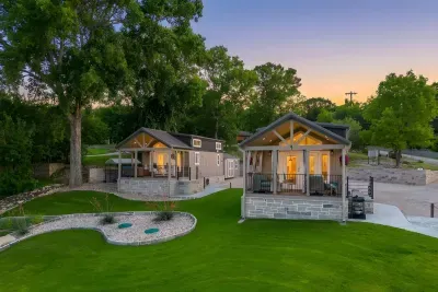 Two tiny homes glowing against the lawn as the sun sets