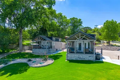 Two modern tiny homes side by side on a sprawling green lawn