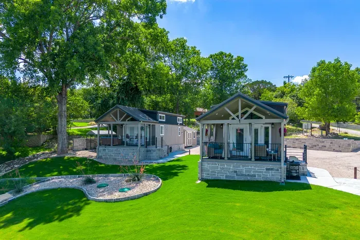 Two modern tiny homes side by side on a sprawling green lawn
