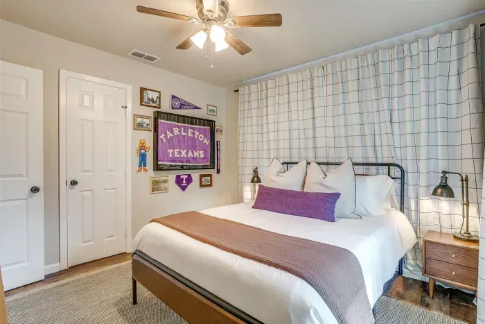 Tarleton pride shines in this queen bedroom with themed wall and soft linens