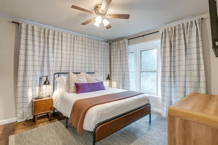 Queen bed in Tarleton-themed room with cozy decor and custom artwork