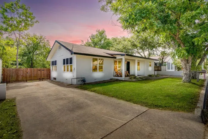 Front of the home with charming curb appeal, shade trees, and large driveway