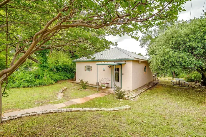 Wide view of the front yard and surrounding shade trees — a peaceful retreat with a welcoming entrance.