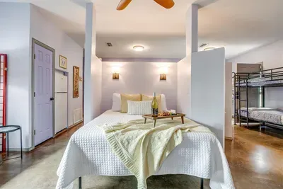 Queen bed with cozy linens and nearby privacy dividers to create separation from the living area and bunks.