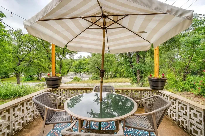 Back patio with umbrella, string lights, and seating for four — enjoy meals outdoors with river breezes and scenic views.