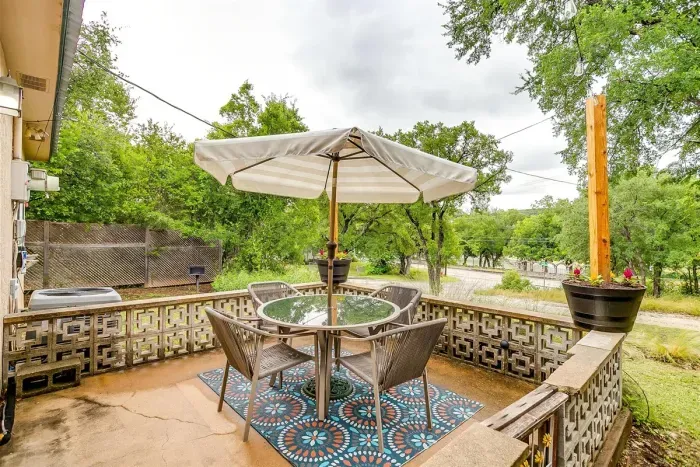 Back patio with umbrella, string lights, and seating for four — enjoy meals outdoors with river breezes and scenic views.