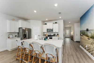 The kitchen island, paired with Serena & Lily chairs, creates a stylish coastal setting—perfect for gathering, sharing meals, and making memories