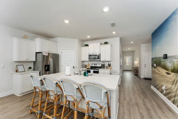 The kitchen island, paired with Serena & Lily chairs, creates a stylish coastal setting—perfect for gathering, sharing meals, and making memories
