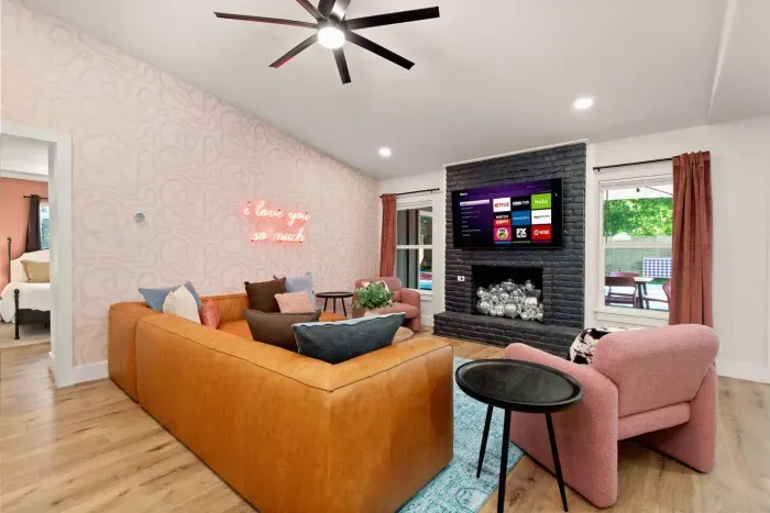 Open concept living area with a leather sectional, neon sign, 65" Roku TV, vaulted ceilings, and disco ball fireplace!