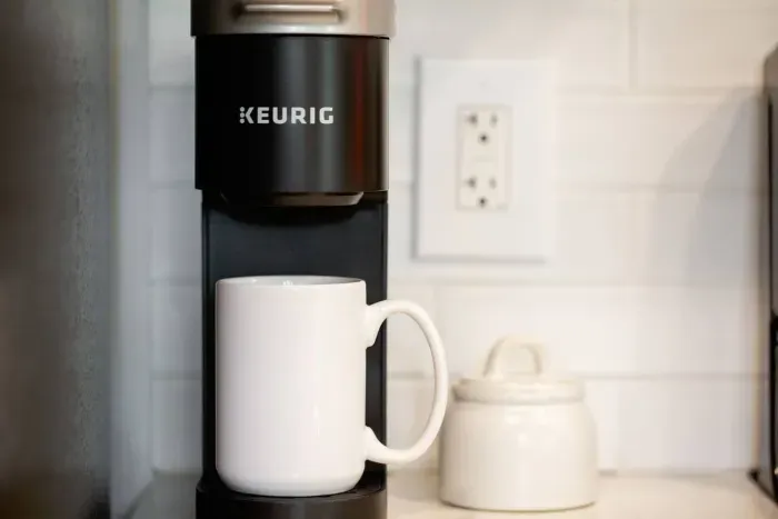 Coffee station with Keurig Mini and drip coffee pot stocked with K-cups, ground coffee, sugar, and creamer