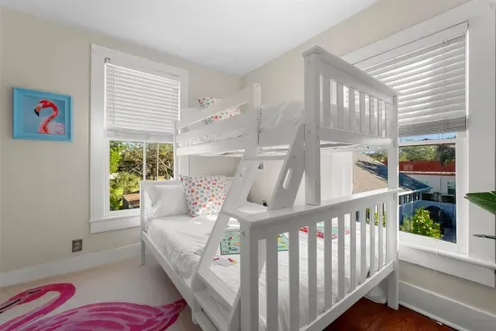 A playful space with a twin-over-full bunk bed, flamingo decor, and bright natural light.