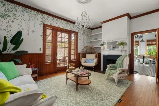 Natural light streams through the French doors, highlighting the greenery and the room’s thoughtfully curated decor. A perfect space for afternoon teas or morning coffees.