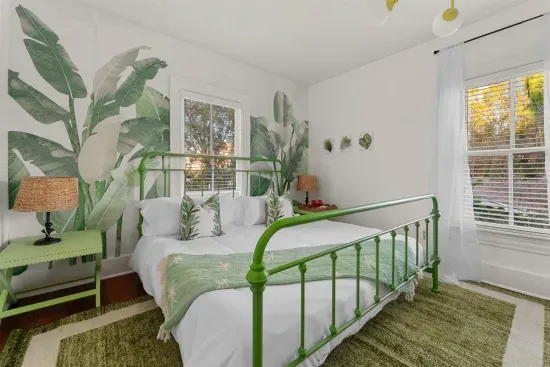 A stunning botanical retreat with a vibrant green bed frame and leafy wall mural for a touch of nature.