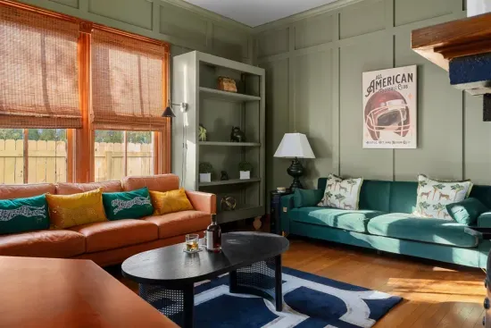 This inviting space combines modern design with rich, vintage tones. Relax on the plush leather and velvet seating as sunlight streams through the large windows, creating a warm and sophisticated ambiance