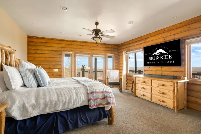 Main floor bedroom with a luxury king bed, 65" smart TV, and high-end surround sound speaker system.