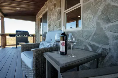 The expansive covered deck has 4 premium chairs with a large gas grill.