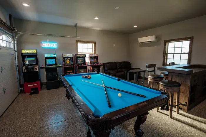 The premium finished garage features an 8' pool table, multiple unlimited-play arcade machines, a bar w/mini fridge, and brand new 4k 75" TV!
