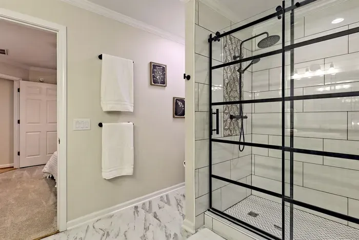 Step into luxury in this stylish Jack & Jill bathroom featuring a sleek, black-framed glass shower with modern tile accents & a rainfall showerhead. With easy access from the adjoining bedrooms, this space is thoughtfully designed for convenience & comfort