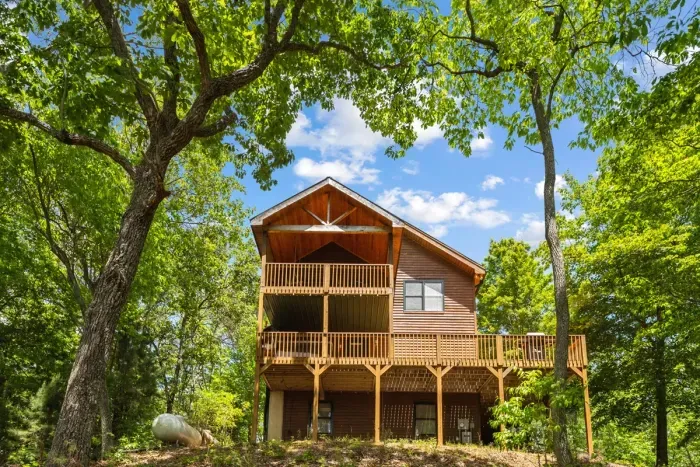 Elevated cabin setting surrounded by trees for added privacy.