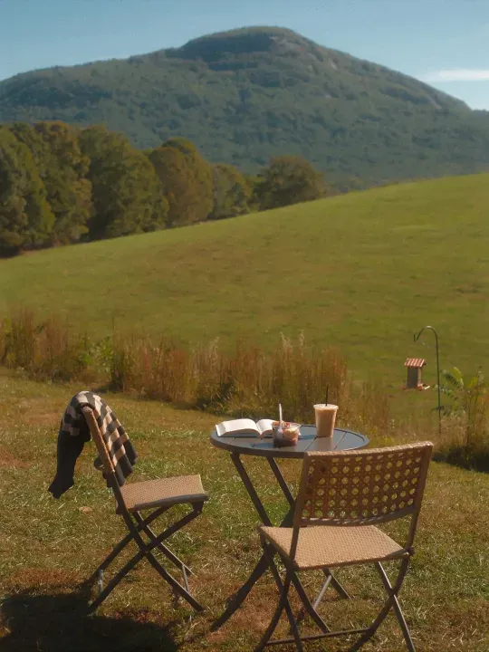 Coffee and outdoor seating overlooking a grassy hillside at Jumping Goats Coffee in Cleveland, Georgia
