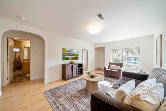 Open-concept living room with "The Frame" smart TV. Sofa has been updated to a modern leather sofa with two new accent seats.