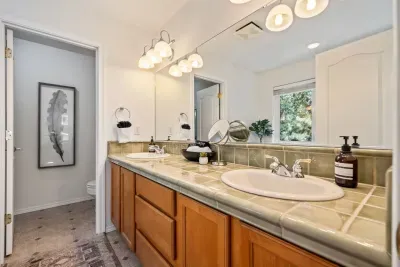 Primary ensuite bathroom with double sinks, soaking tub, and separate room with toilet and standing shower