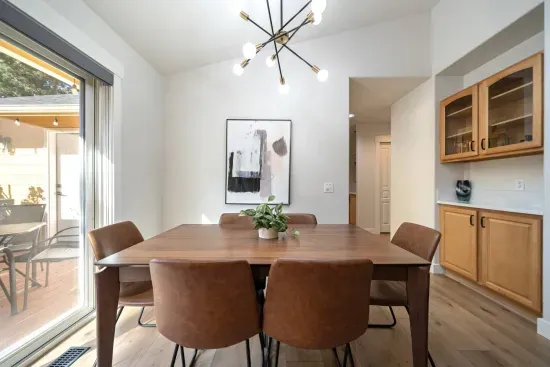 Dining room with comfortable, easily wipeable seating with modern sputnik chandelier and books and board games in the cabinet nearby