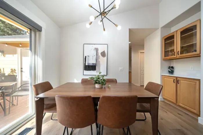 Dining room with comfortable, easily wipeable seating with modern sputnik chandelier and books and board games in the cabinet nearby