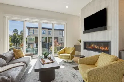 Sunlit modern lounge with fireplace, TV, and oversized glass doors
