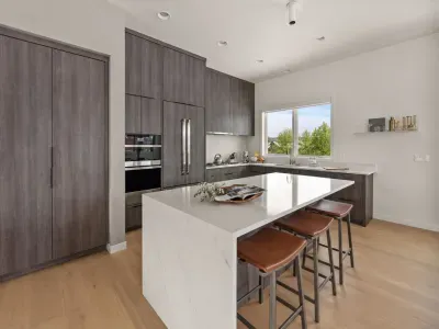 Modern chef’s kitchen with waterfall island, seating, and sunny window views