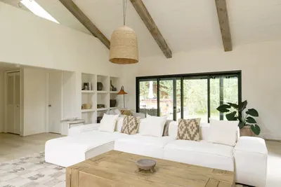Bright vaulted living room with chic white sectional and garden views