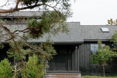 Modern dark-wood exterior framed by lush greenery and a private entry