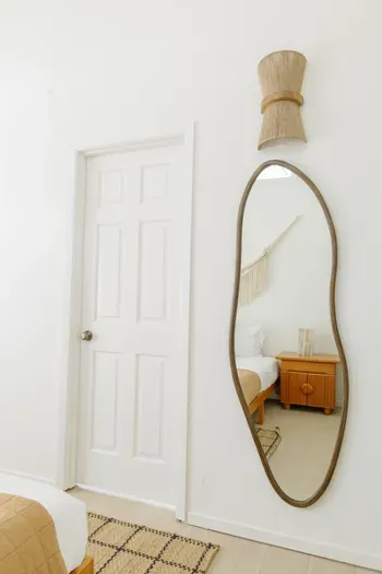 Bright minimalist bedroom with full-length mirror and warm natural accents